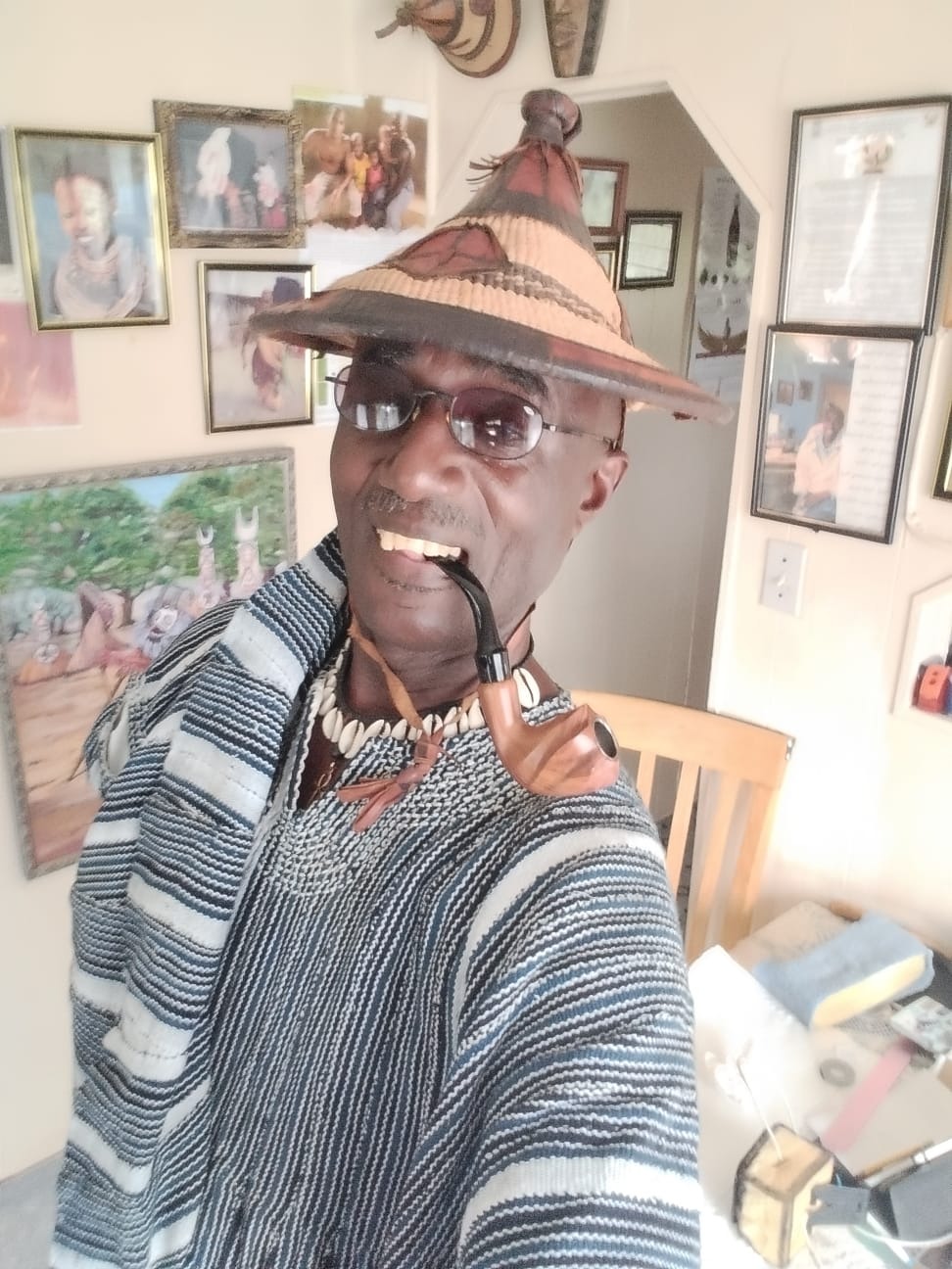 A close-up of an artist passionately painting on a large canvas, surrounded by colorful paint splatters. The canvas depicts vibrant cultural symbols and ancestral motifs, highlighting the artist's joyful expression. Natural light streams in, illuminating the creative space filled with brushes and tools.